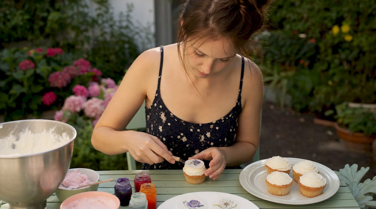 Alguém a decorar um cupcake com uma imagem comestível por cima
