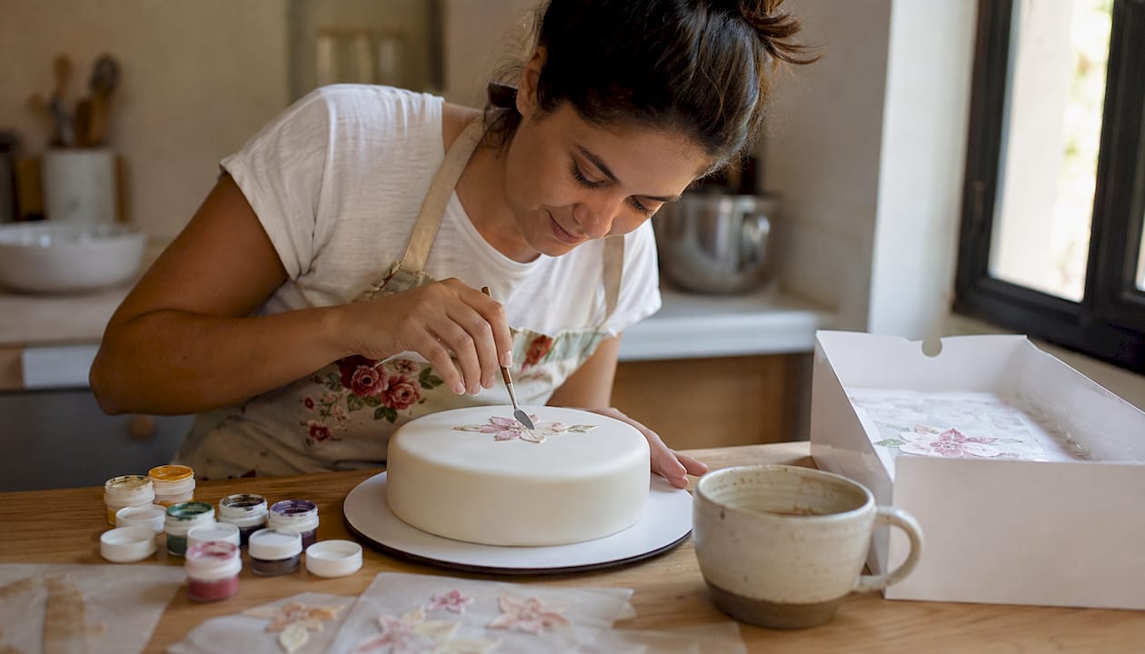 Especialista em pastelaria a decorar um bolo com folha de obreia
