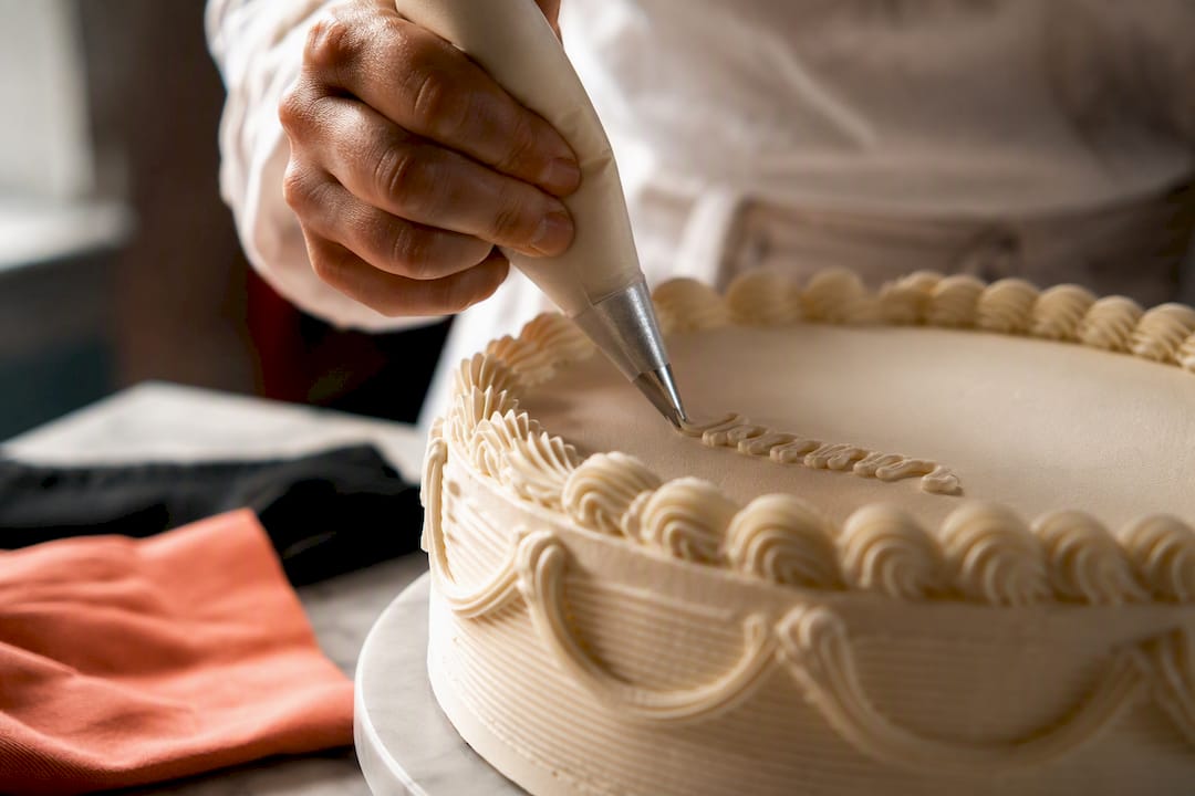Mão a escrever uma mensagem curta no bolo