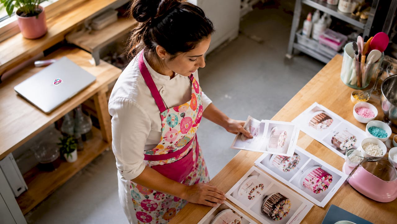 Repostera revisando diseños impresos para decorar tartas