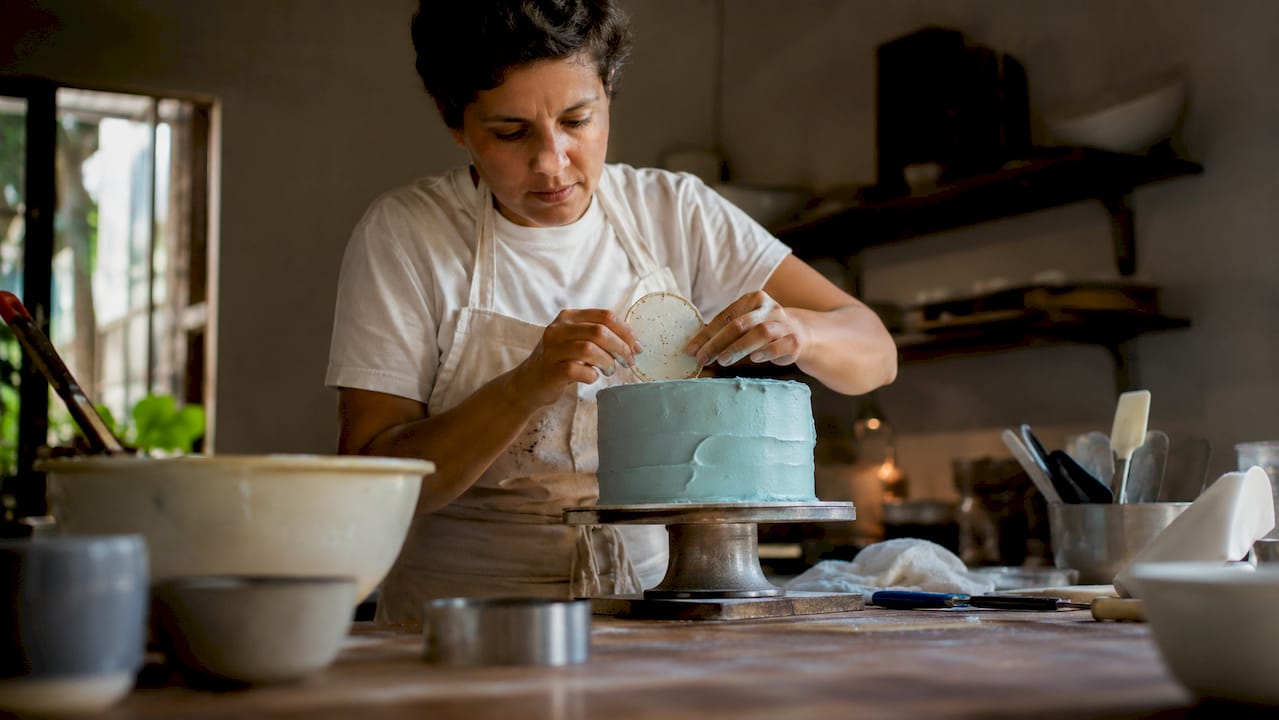 Pastelheira a decorar o bolo com um topper comestível