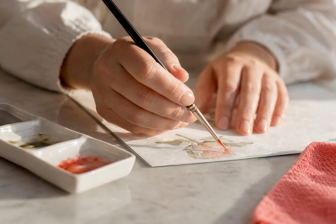 Mãos a pintar papel comestível com um pincel